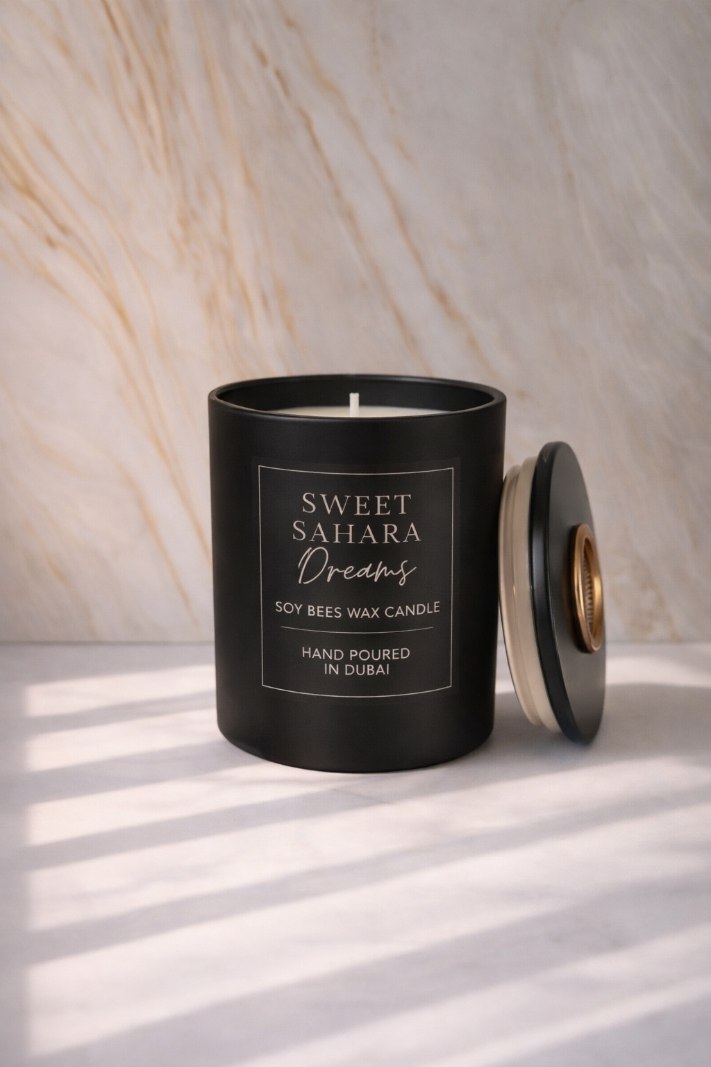 Black candle with 'Sweet Sahara Dreams' text on a marble background
