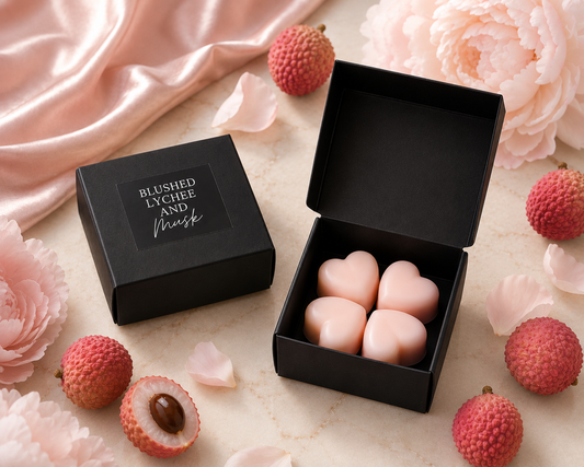 Pink heart-shaped candies in a black box with lychees and flowers on a light background